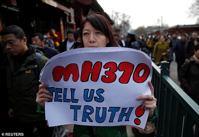 Catherine Gang, whose husband Li Zhi was on board Malaysia Airlines flight MH370, holds a banner saying the passengers' families want the truth.
