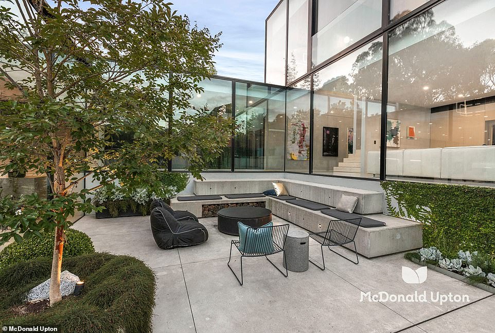 Outside, vine walls surround a lawn area and a 15-metre heated pool, while built-in concrete seating creates a relaxing entertaining space with a fire pit.