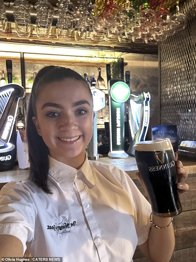 Olivia appears in the photo in her work uniform standing next to the bar.