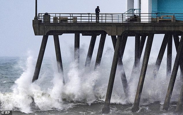 Waves crash against the pilings of the Huntington Beach Pier in Huntington Beach as another storm brought strong waves, rain, winds and cool temperatures to Southern California.