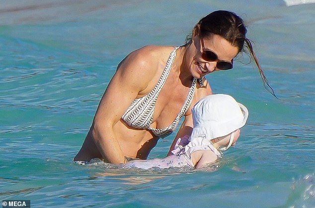 The mother of three was occasionally seen wearing rounded tortoiseshell sunglasses while wading in and out of the water.