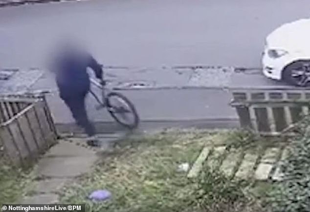 The thief calmly carries the bicycle to his van.