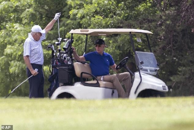 President Joe Biden sits in a golf cart while playing golf with his brother Jim.