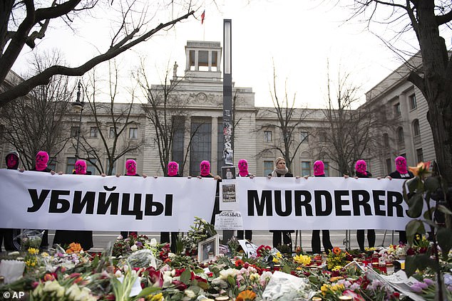 Members of the Russian activist group Pussy Riot hold a sign outside the Russian embassy in Berlin on February 18, 2024, following the shocking death of opposition leader Navalny.