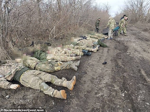 Dead soldiers are lined up as comrades prepare body bags.