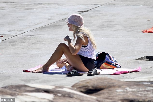 The petite blonde accessorized with a pink bucket hat and black sandals.