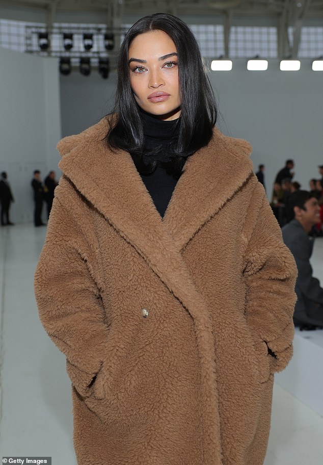 The model covered a black ensemble with the coat reaching to her shins, while highlighting a high-necked blouse and long pointed patent leather boots.