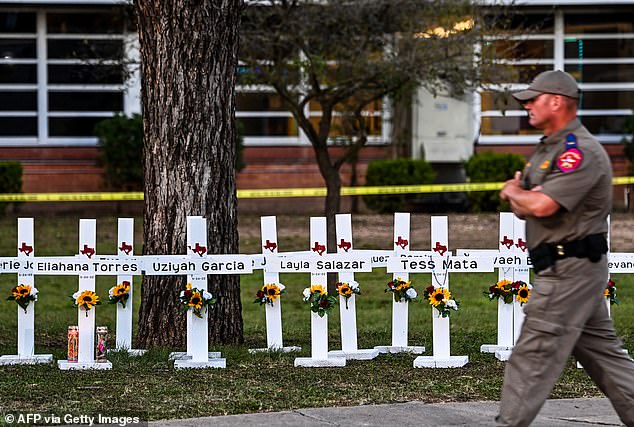 Police officers walk past a memorial to the victims of the Robb Elementary School shooting in Uvalde, Texas, on May 26, 2022.