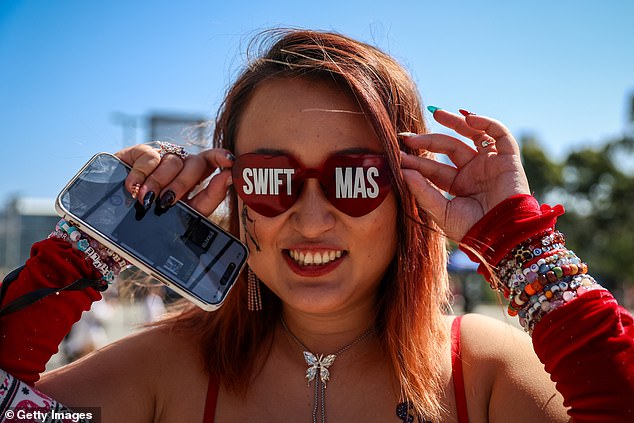 A Taylor Swift fan poses for a photo wearing glasses that say Swiftmas
