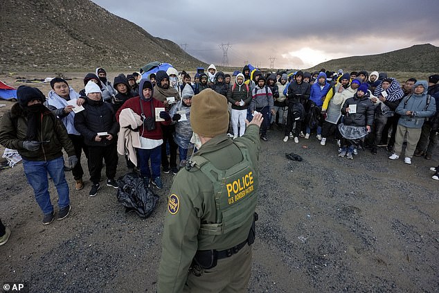 A Border Patrol agent asks asylum-seeking migrants to line up at a makeshift mountain camp after the group crossed the border into Mexico, Friday, Feb. 2, 2024, near Jacumba Hot Springs.