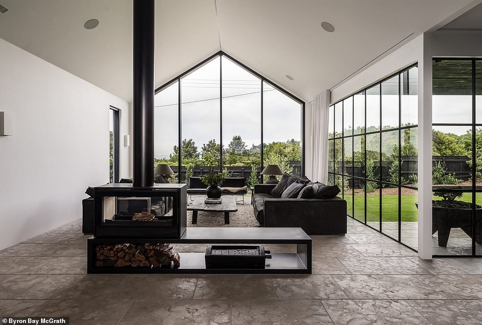 The open living room, kitchen and dining room are the epicenter and brightest room in the house with white walls, limestone floors and ceiling-high windows that let in natural light.