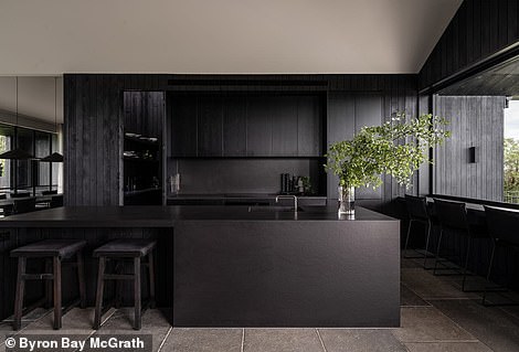 Unlike the rest of the family room, the kitchen is completely black from the island bench to the backsplash, cabinets, hidden bar, and even the sink.