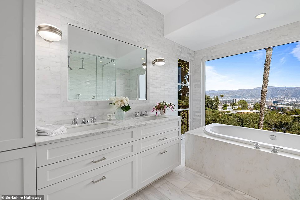 The bathroom features a luxurious tub complete with dual vanities, a jetted tub with window views, and a large glass shower.