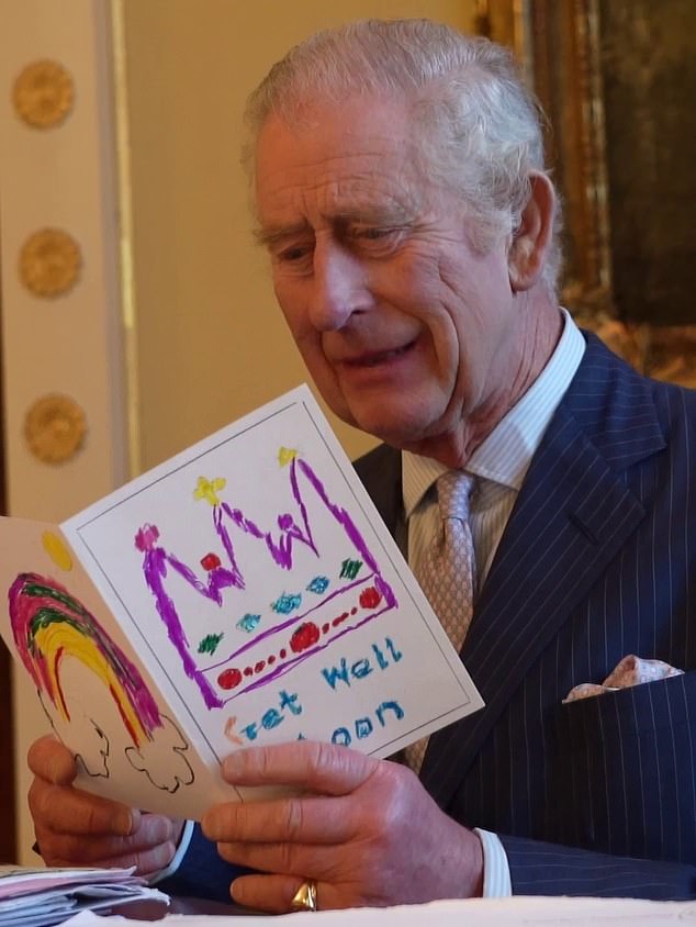 The King opens a card with hand-drawn drawings of a rainbow and a multi-coloured crown sent to Buckingham Palace by a child