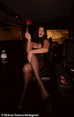 She wore sheer, shiny stockings, black heels and wrapped a black scarf around her head while singing inside a vehicle.