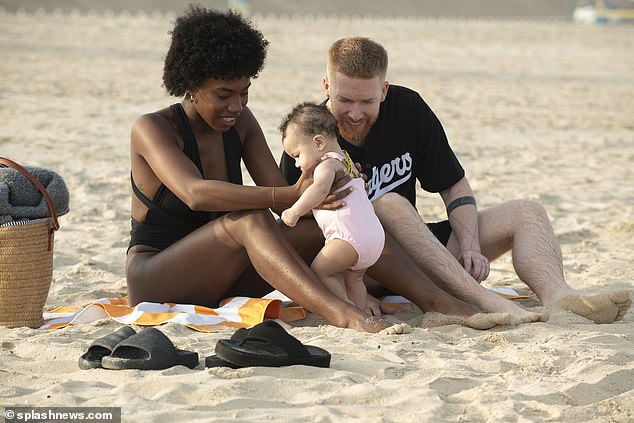 Meanwhile, Neil cut a casual figure in an oversized black t-shirt and matching shorts as the trio played in the sand.