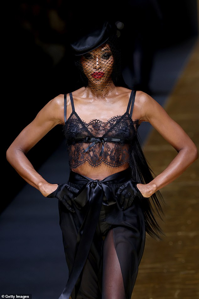 Supermodel Naomi, 53, gave a glimpse of her midriff as she walked the catwalk in a sheer black lace top.