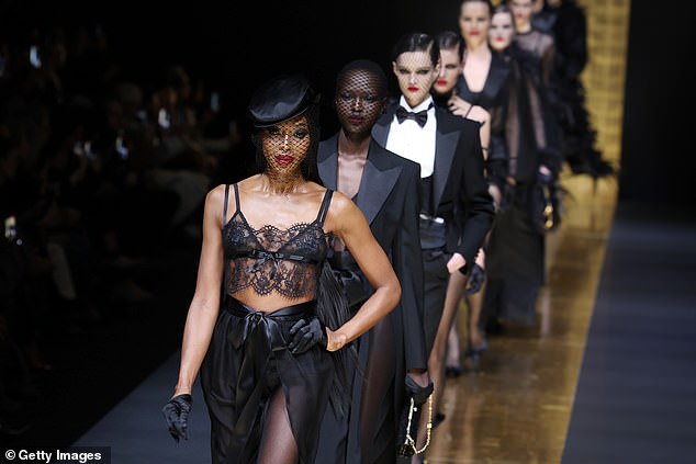 Fashionista Naomi wore a black hat tilted on her head with a net veil, while she wore a pair of black gloves and heels of the same color.