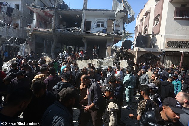 People gather in front of a building destroyed in the Rafah airstrike. At least eight people died