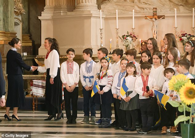 A group of children hold Ukrainian flags inside the Royal Chapel in Stockholm.