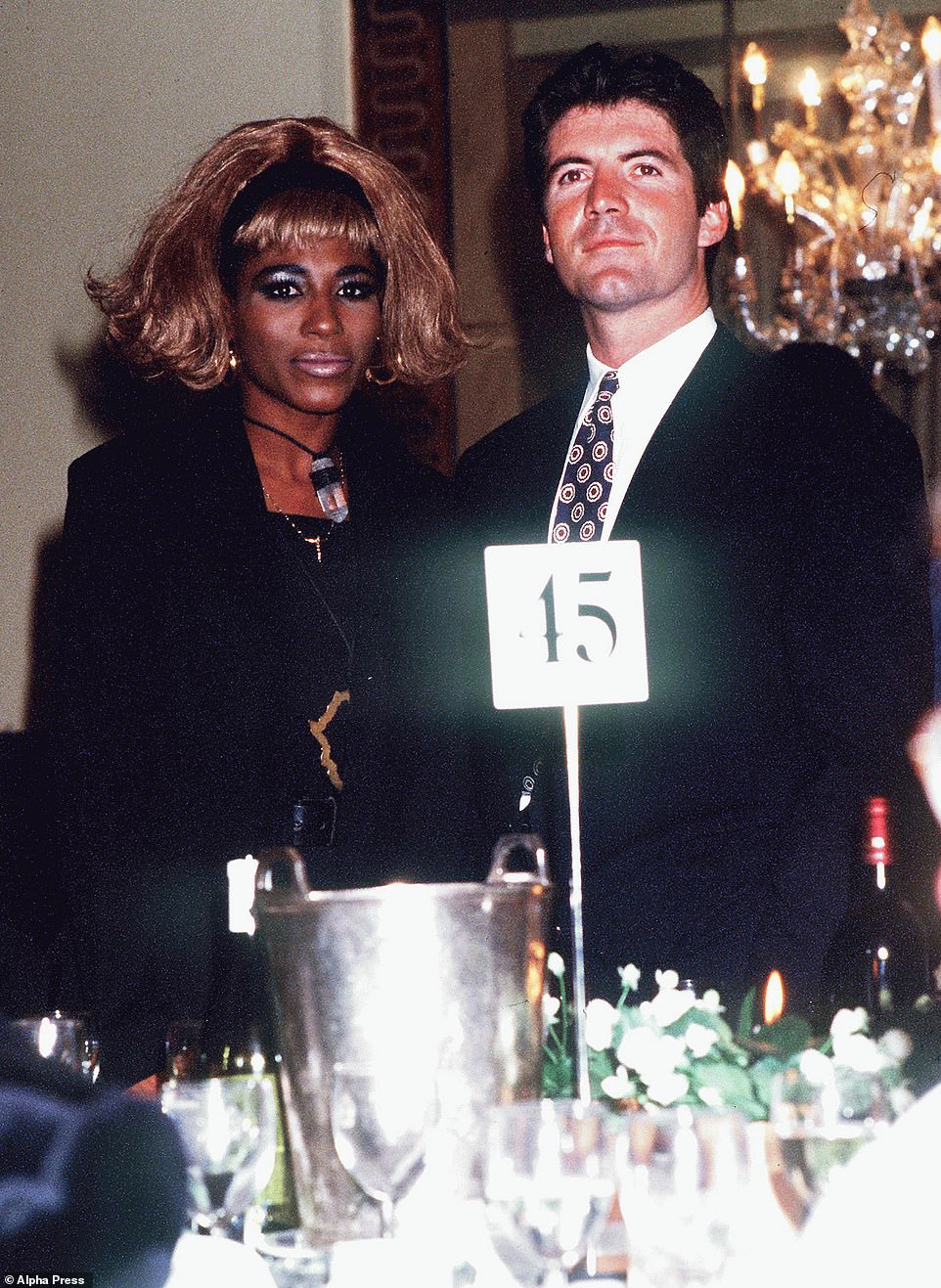 1990: Cowell looks handsome while posing with his then-girlfriend Sinitta, a constant in his life, at an event in London