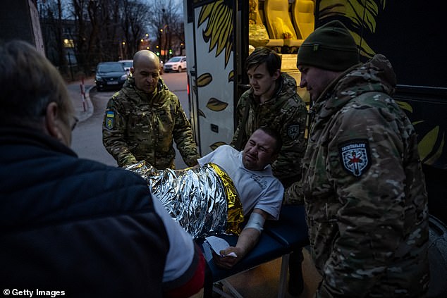 Ukrainian medical volunteers from the Hospitaller Battalion unload wounded Ukrainian soldiers from their medical bus in the critical battle for Avdiivka