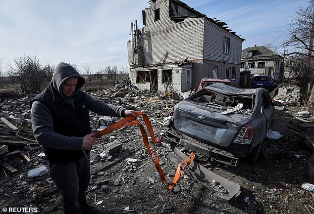 A resident prepares a disabled car to be towed, near a residential building damaged during a Russian drone strike, in Dnipro, Ukraine, on Monday.