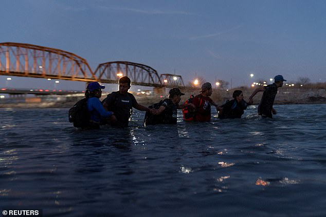 Migrants arm in arm as they enter the Rio Grande River with the intention of crossing to Eagle Pass, Texas.