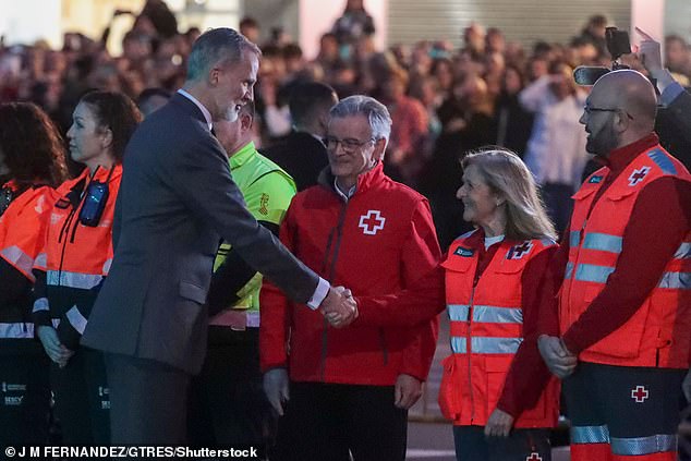 King Felipe shakes hands with a first responder after the deadly fire that killed 10 people on Thursday