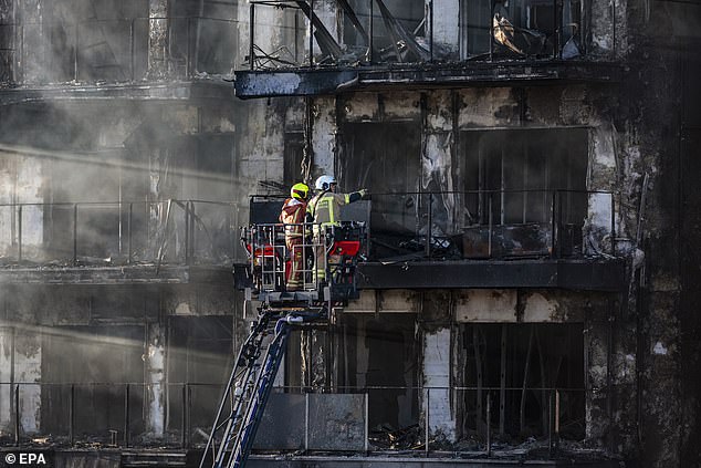 Fire investigators assess the charred hull of the apartment block on Friday after the fire was extinguished.