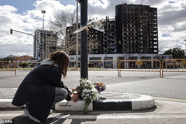 A woman places flowers at the site of the fire on Rafael Alberti Poeta Street in Valencia, which occurred on Thursday afternoon