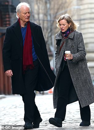 Bill wore a dark blue coat over a light blue shirt and black pants as he walked down a city sidewalk with Naomi, who also kept warm with a colorful scarf.