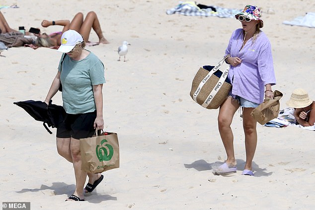 Meanwhile, girlfriend Ramona made sure all eyes were on her in a blue bikini and denim shorts paired with a lavender shawl.  She completed her look with a colorful bucket hat, retro sunglasses and a Chloe bag, and opted to carry a black umbrella.