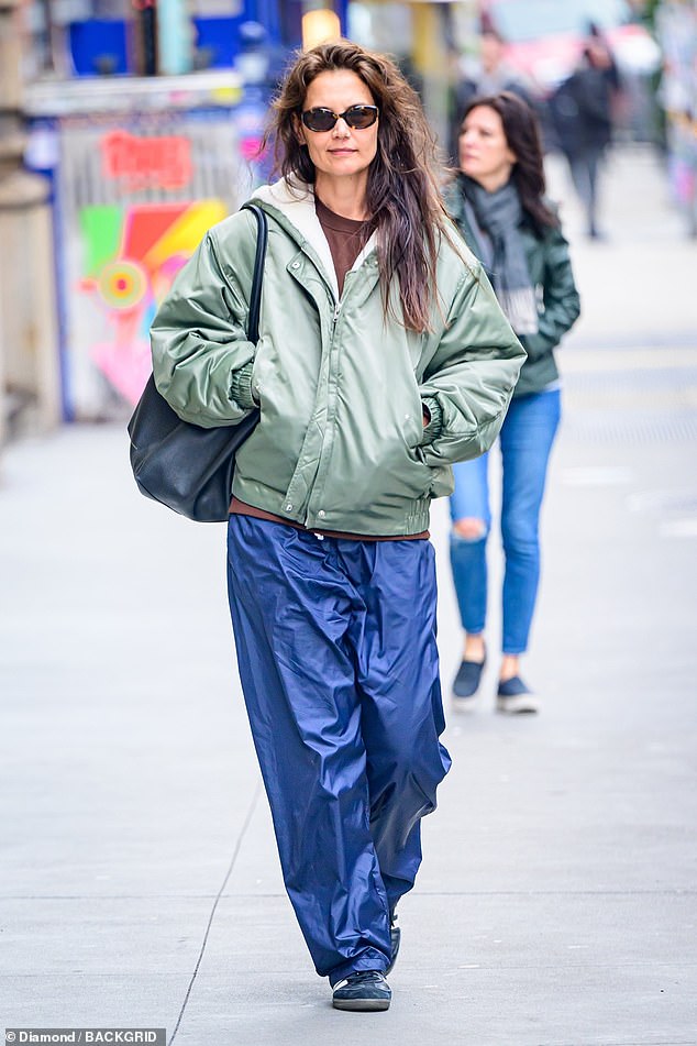 Earlier in the day, Katie cut a casual figure in a khaki coat and eye-catching blue raincoat pants.
