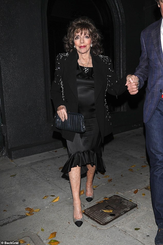 Joan, 90, put on a glamorous display in a black satin midi dress, teamed with an embellished jacket and sparkly heels.