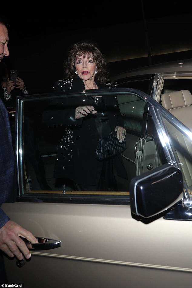 Joan accessorized with chunky silver jewelry and carried a black leather clutch.