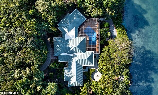 An aerial shot of the house with a pool on the island.