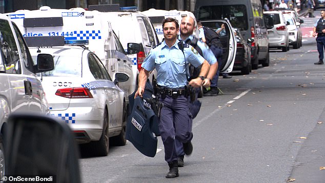 Here, police officers run towards the scene of the shooting on Castlereagh St in Sydney.