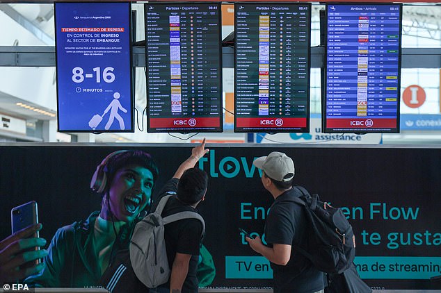 Passengers at the Ministerio Pistarini International Airport look at the flight information screen on Wednesday