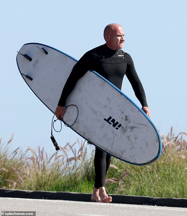 They saw him carrying his board and walking barefoot towards the shore.