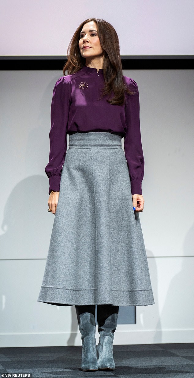 The royal paired her plum-hued ensemble, which she also wore to present a series of research awards in January last year, with a gray skirt that fanned out to create a stunning silhouette.
