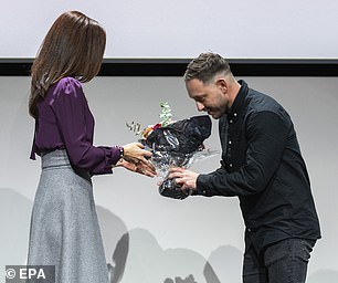 He gave flowers to a man before presenting him with an award.