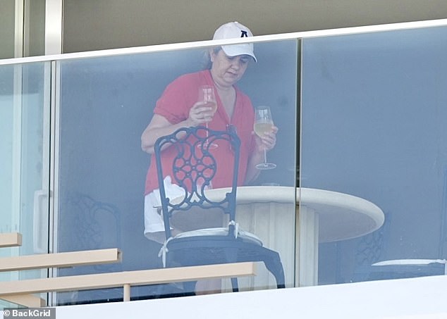 Wearing a white baseball cap, matching white shorts and a casual red T-shirt, Ms Palaszczuk carried two glasses of wine to the balcony overlooking the beach.