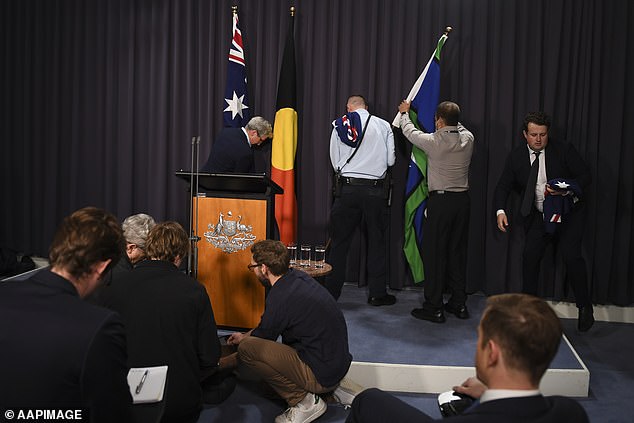 Staff replace two Australian flags in the Blue Room of Parliament with Aboriginal and Torres Strait Islander insignia on Monday.