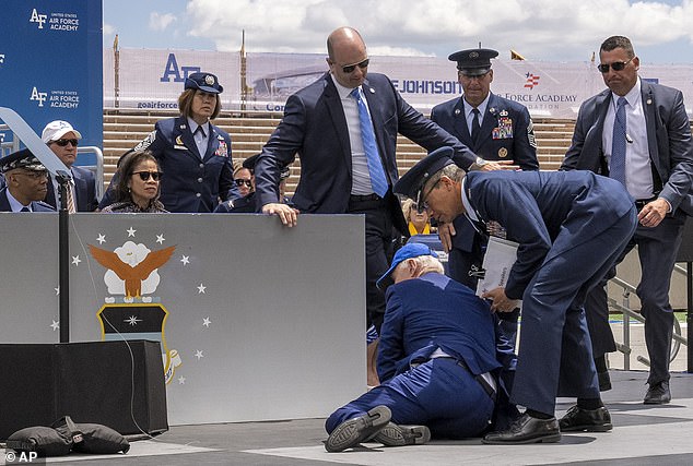 Biden looks at a sandbag as he is helped off the ground after falling on the stage at the Air Force Academy graduation ceremony in Colorado Springs, Colorado, June 1, 2023.