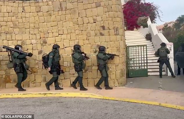 Detectives have described the seizure as one of the largest ever in the Andalusia region of southern Spain.  A team of armed officers can be seen marching towards the house next to the wall before slowly ascending the stairs.