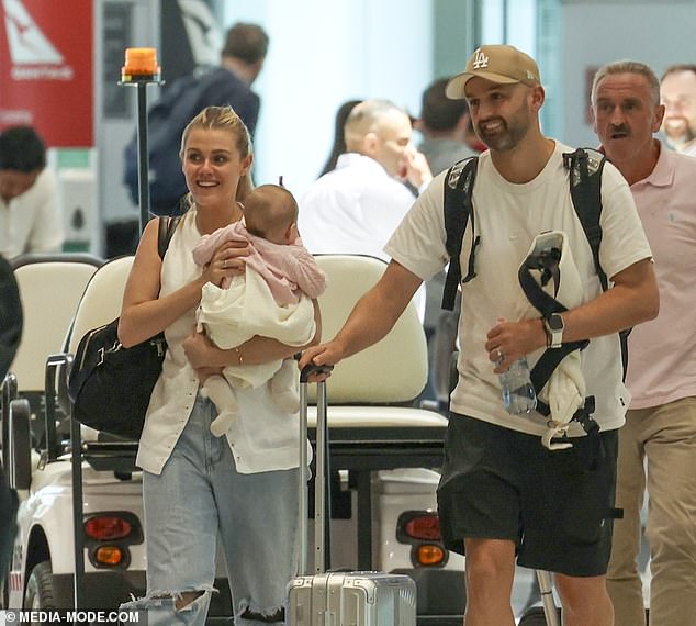 Cricketer Nathan Lyon and his wife Emma arrive in Sydney with their rarely-seen child after secret pregnancy – as doting mother shows off her post-baby body in ripped jeans