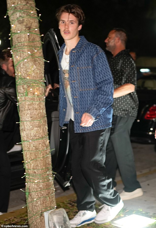 Cruz Beckham wore a T-shirt with a photo of one of his iconic childhood moments while heading out for steak dinner at Papi Steak with his dad David in Miami on Thursday.