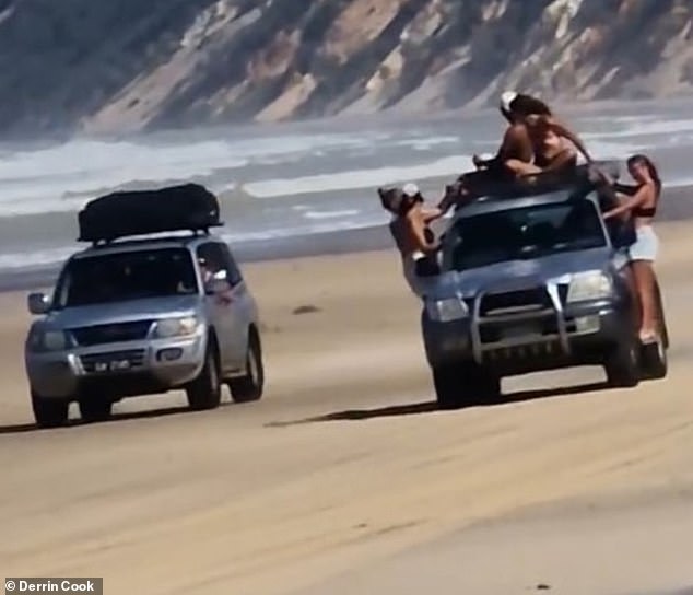 A silver Toyota Landcruiser was filmed traveling along Rainbow Beach, Queensland, with five people hanging on the outside of the vehicle while another 4x4 drove alongside.