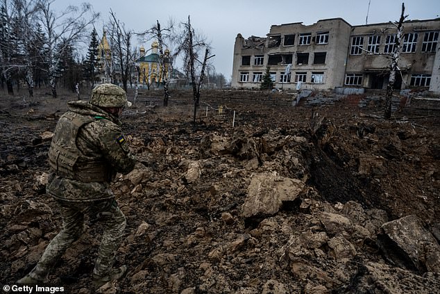 Ukrainian officer Maksym Radchenko walks amid the devastation caused by a Russian glide bomb that landed on a road near a school in the village of Petropavlivka, as the Ukrainian armed forces strengthen their defensive positions and Russian troops investigate the front line .